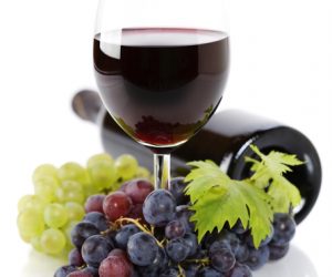 A Glass Of Red Wine & Grapes Over White